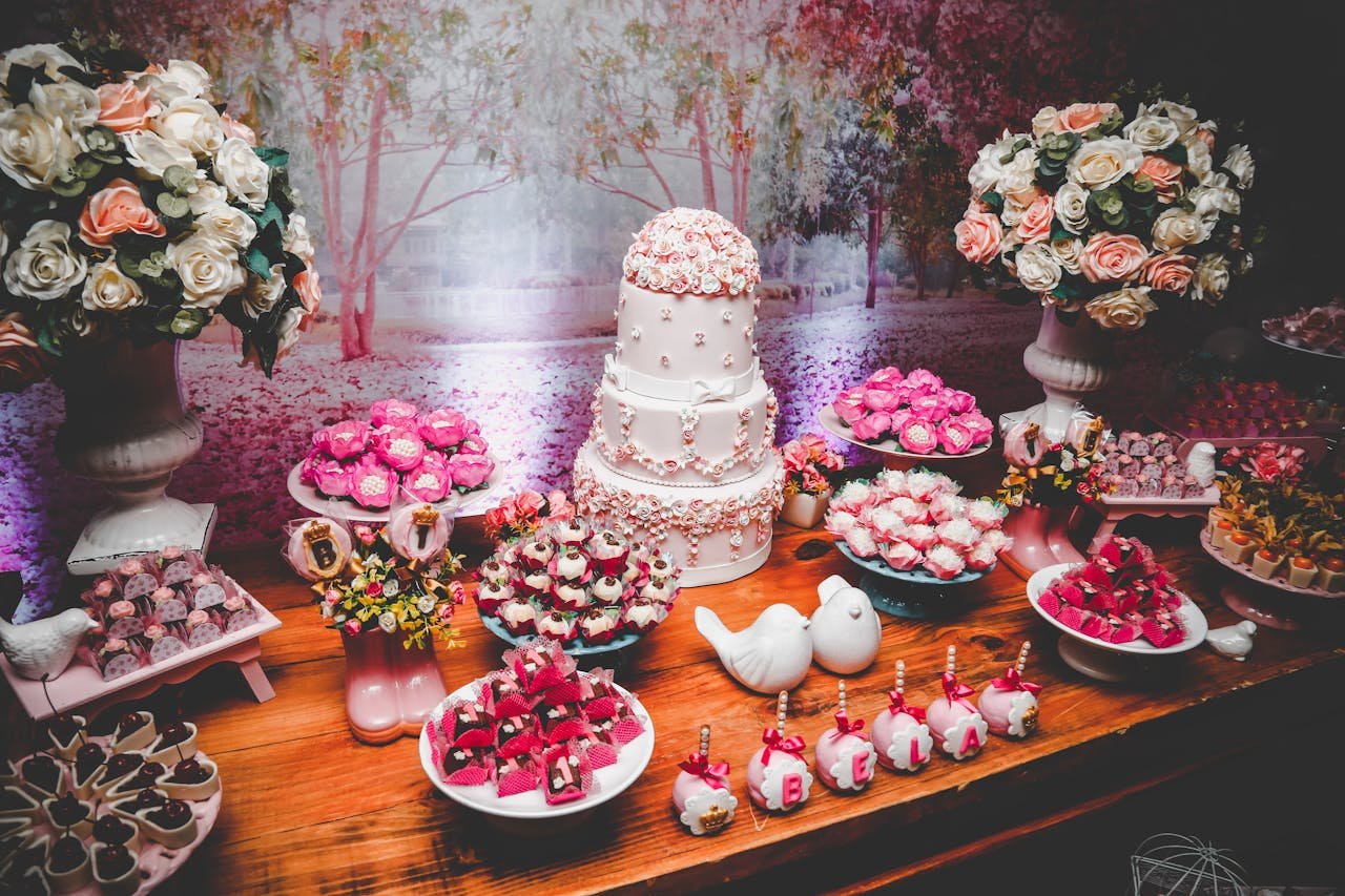 A beautifully arranged dessert table featuring a tiered cake, sweets, and floral arrangements.