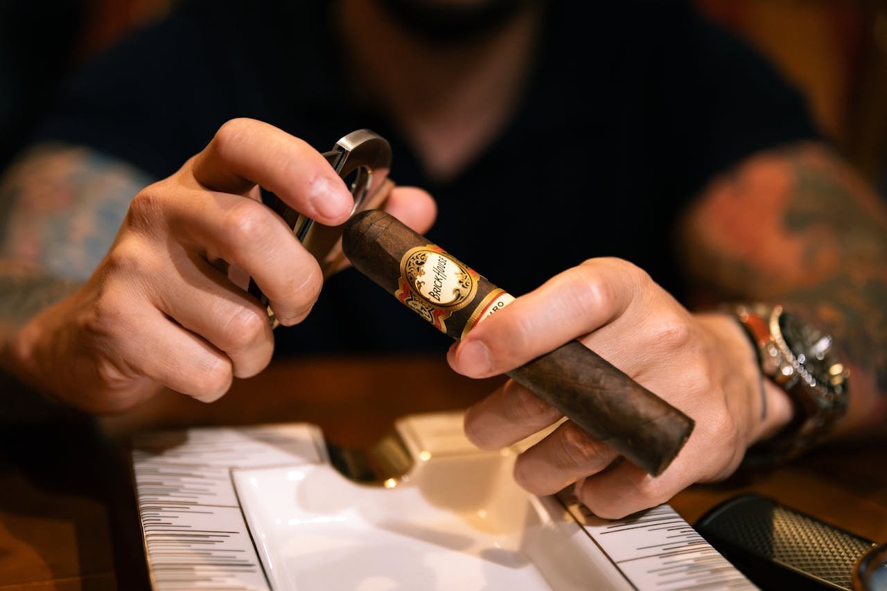 A detailed close-up of a man carefully cutting a cigar, showcasing precision and craftsmanship.